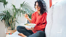 woman eating healthy meal in a red jumper sat in living room