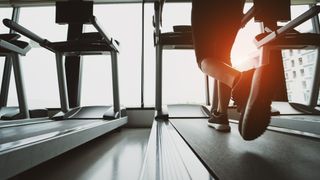 Feet of a person running on a treadmill in a gym