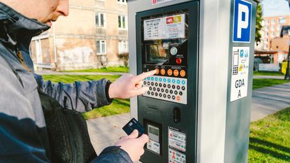man pays for parking at car parking meter