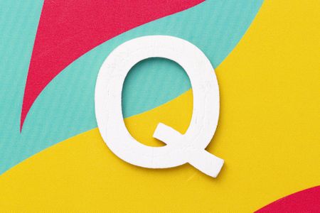 the letter "Q" on a colorful background of red, blue, and yellow