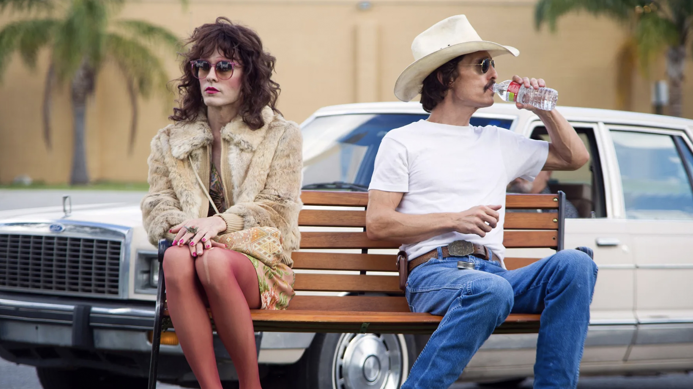 A still from the movie Dallas Buyers Club in which Jared Leto's character Rayon sits on a bench with Matthew McConaughey as Ron Woodroof.
