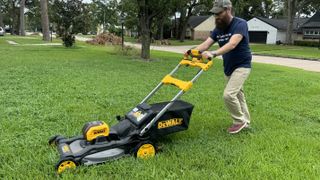 Man pushing mower across grass