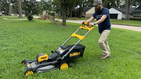 Man pushing mower across grass