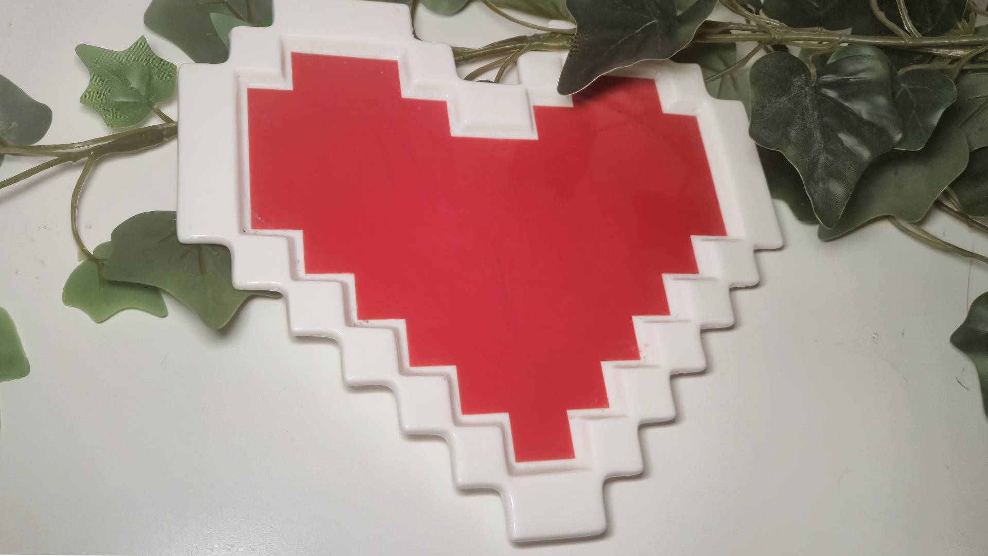 Photo of a heart-shaped Legend of Zelda plate on a white desk.