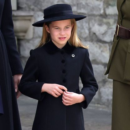 Princess Charlotte wearing a black dress coat and hat with a horseshoe brooch