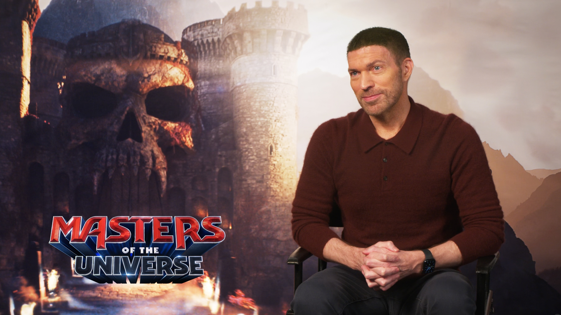 Director Travis Knight sits in front of a "Masters of the Universe" poster. 
