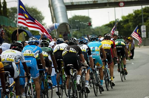The peloton pass by more Malaysian flags roadside on stage seven.