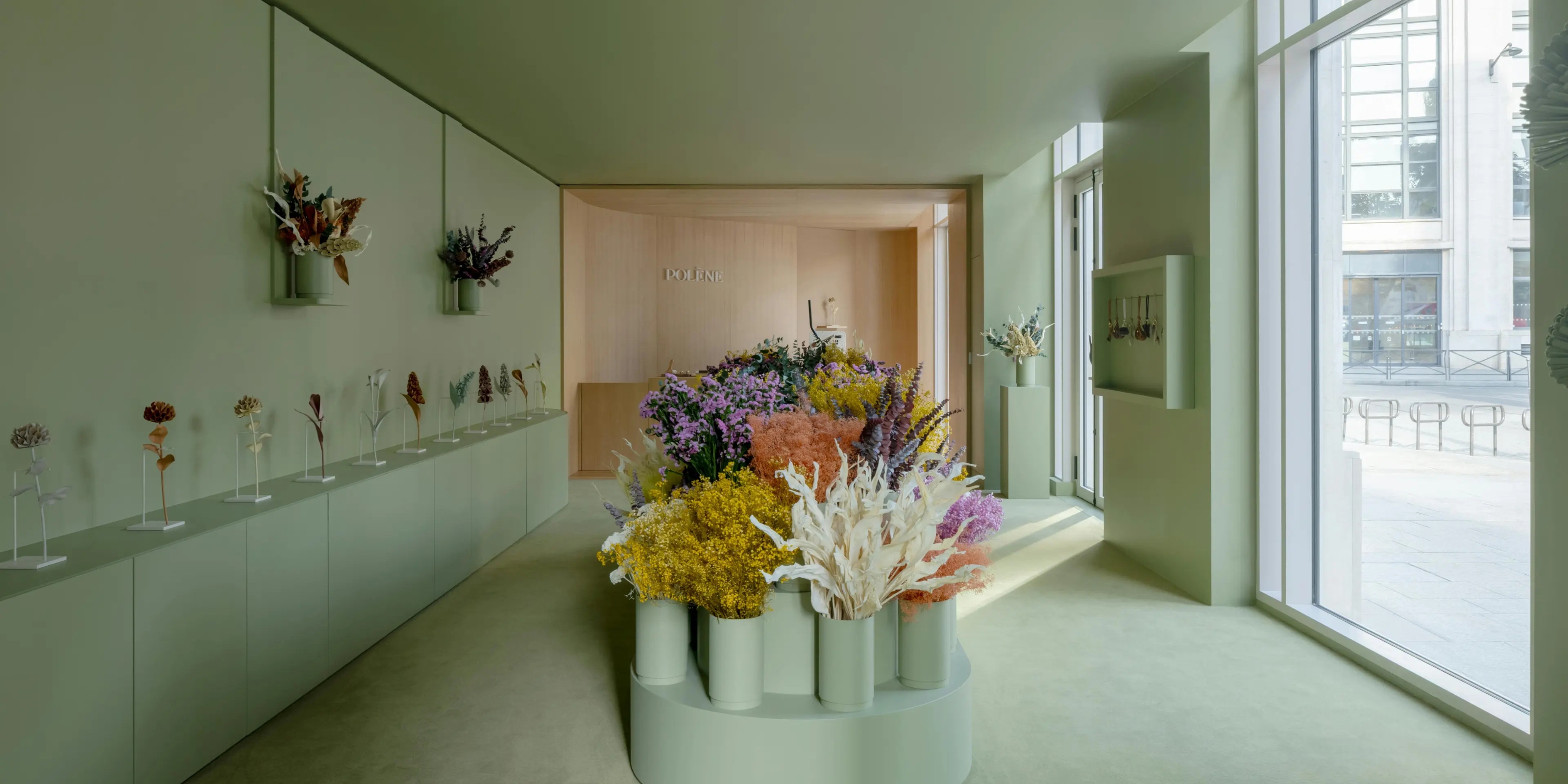 A mint-tinted gallery room houses a florist shop characterized by colorful blooms and essential decor.