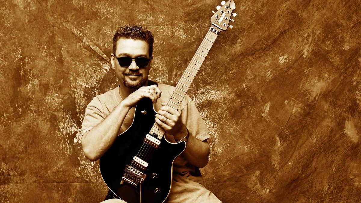 Posed full length studio portrait of Eddie Van Halen with a Peavey guitar