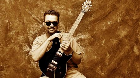 Posed full length studio portrait of Eddie Van Halen with a Peavey guitar