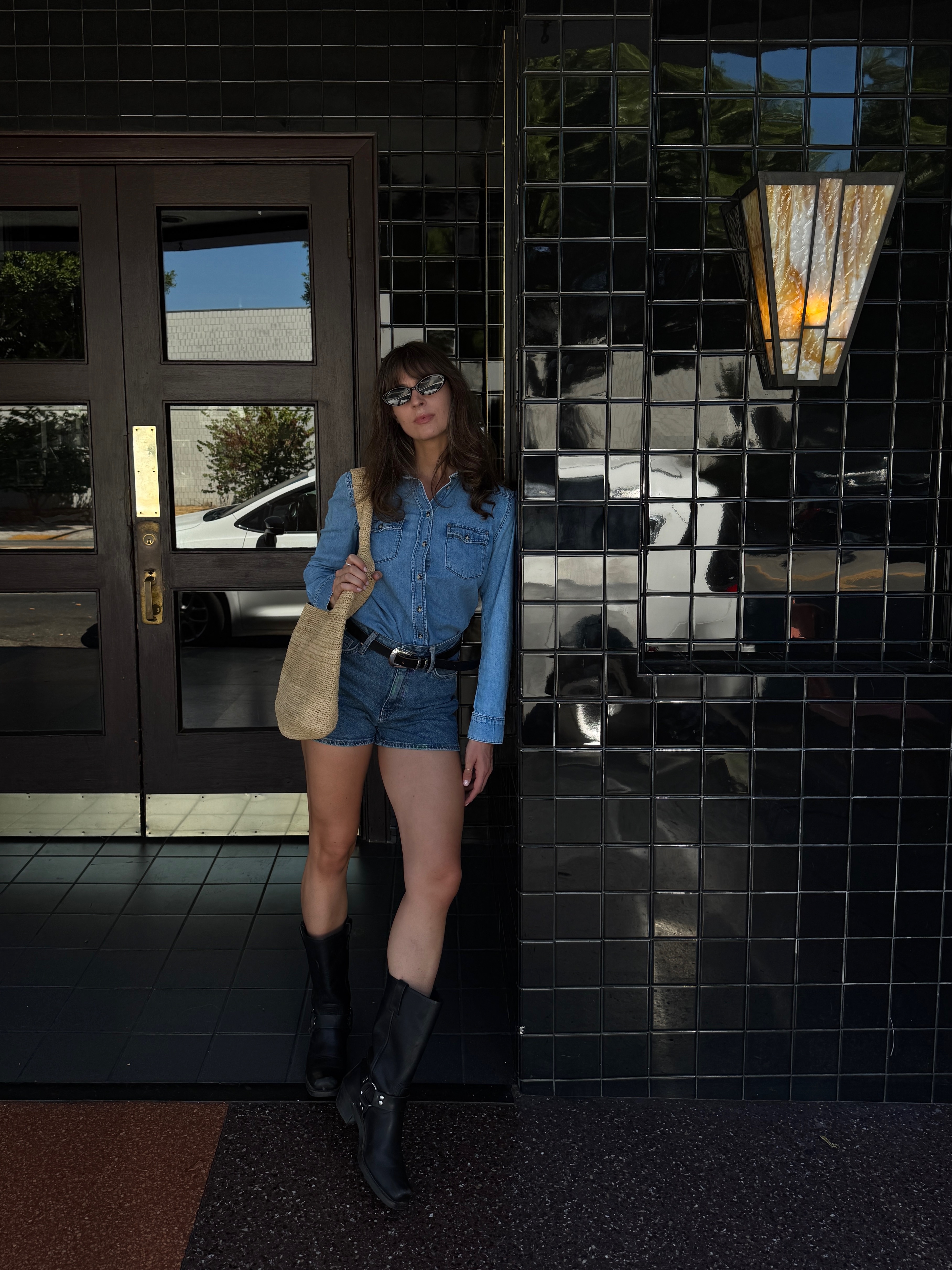 Kathryn Zahorak wearing sunglasses, denim shirt, denim shorts, and black boots