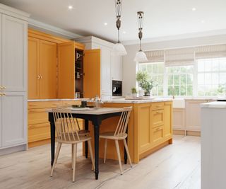 yellow kitchen with low-level kitchen table and larder unit