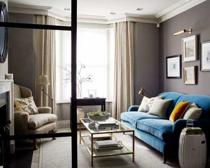 How long should curtains be: Luxe living room with crittal doors and long luxurious curtains against a blue velvet sofa