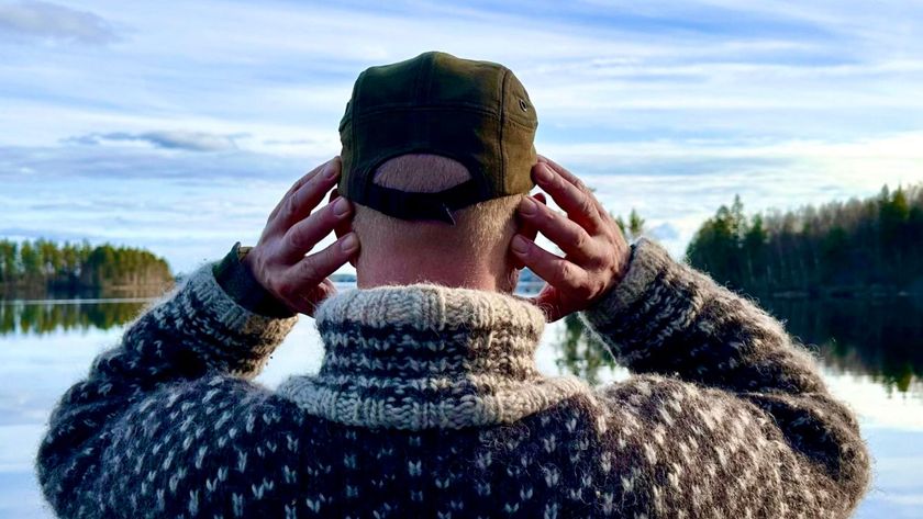 man with hands over ears in front of a lake