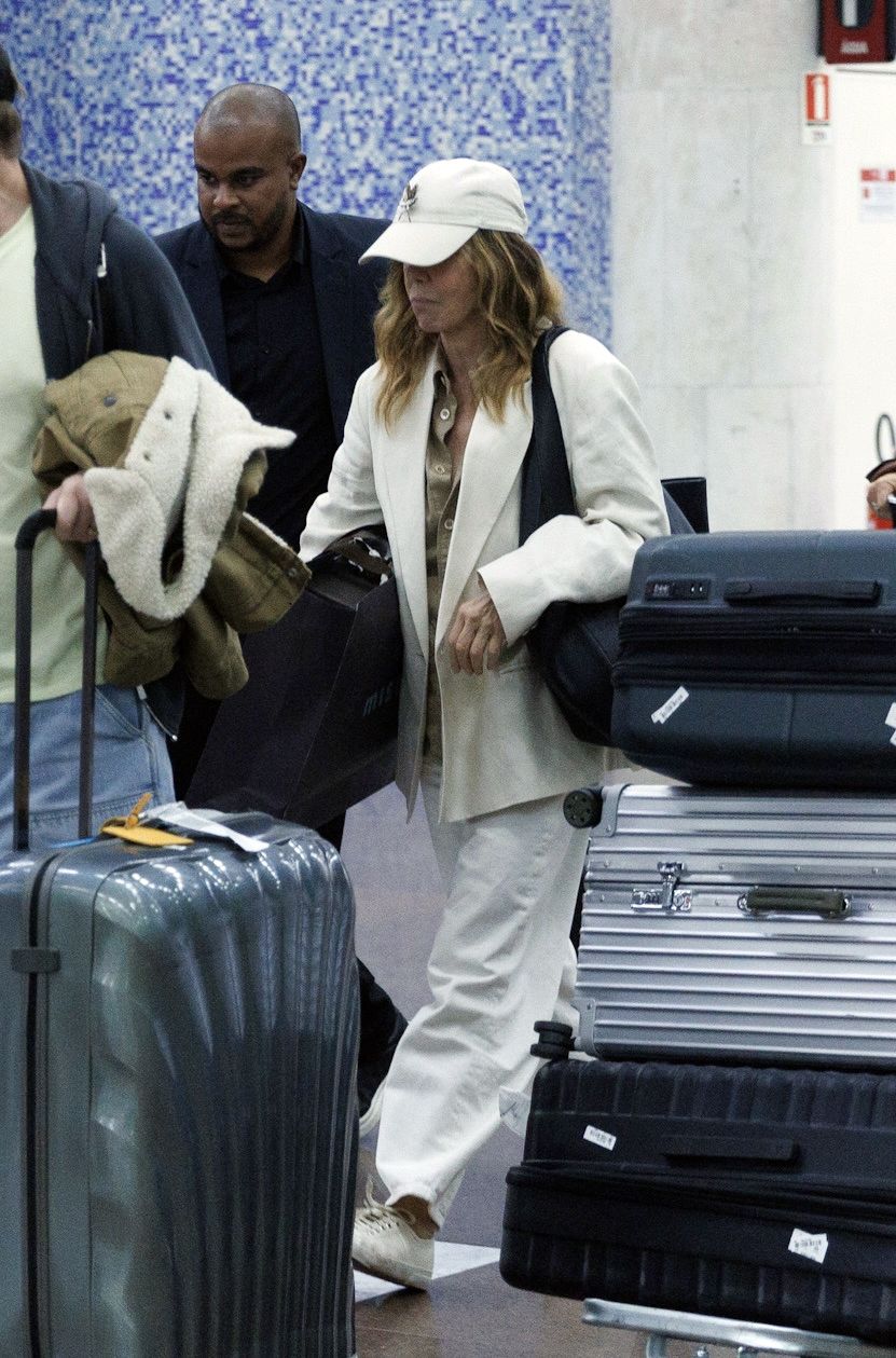 Philippine Leroy-Beaulieu walks through the airport wearing white trainers with white jeans and a white blazer.