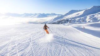 Woman skiing down mountain against blue sky