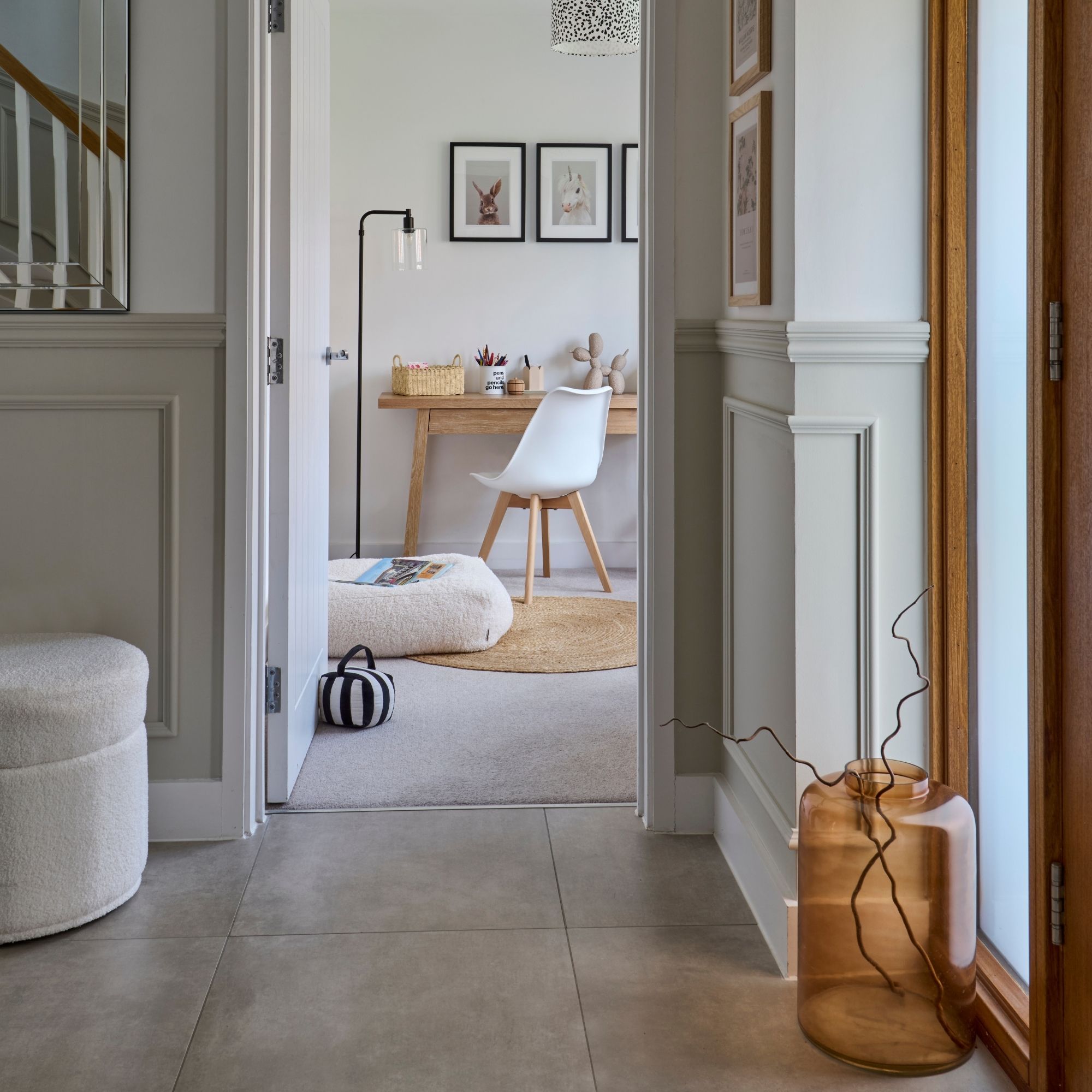 Neutral painted hallway looking into a home office with a wooden desk and a white chair