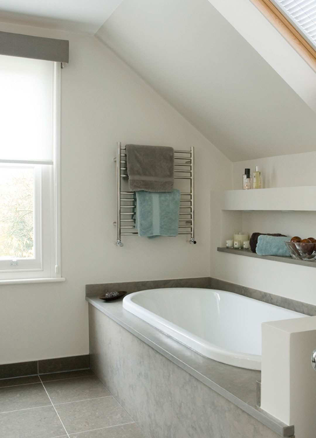 modern grey and white bathroom with small heated towel warmer at the end of the bath