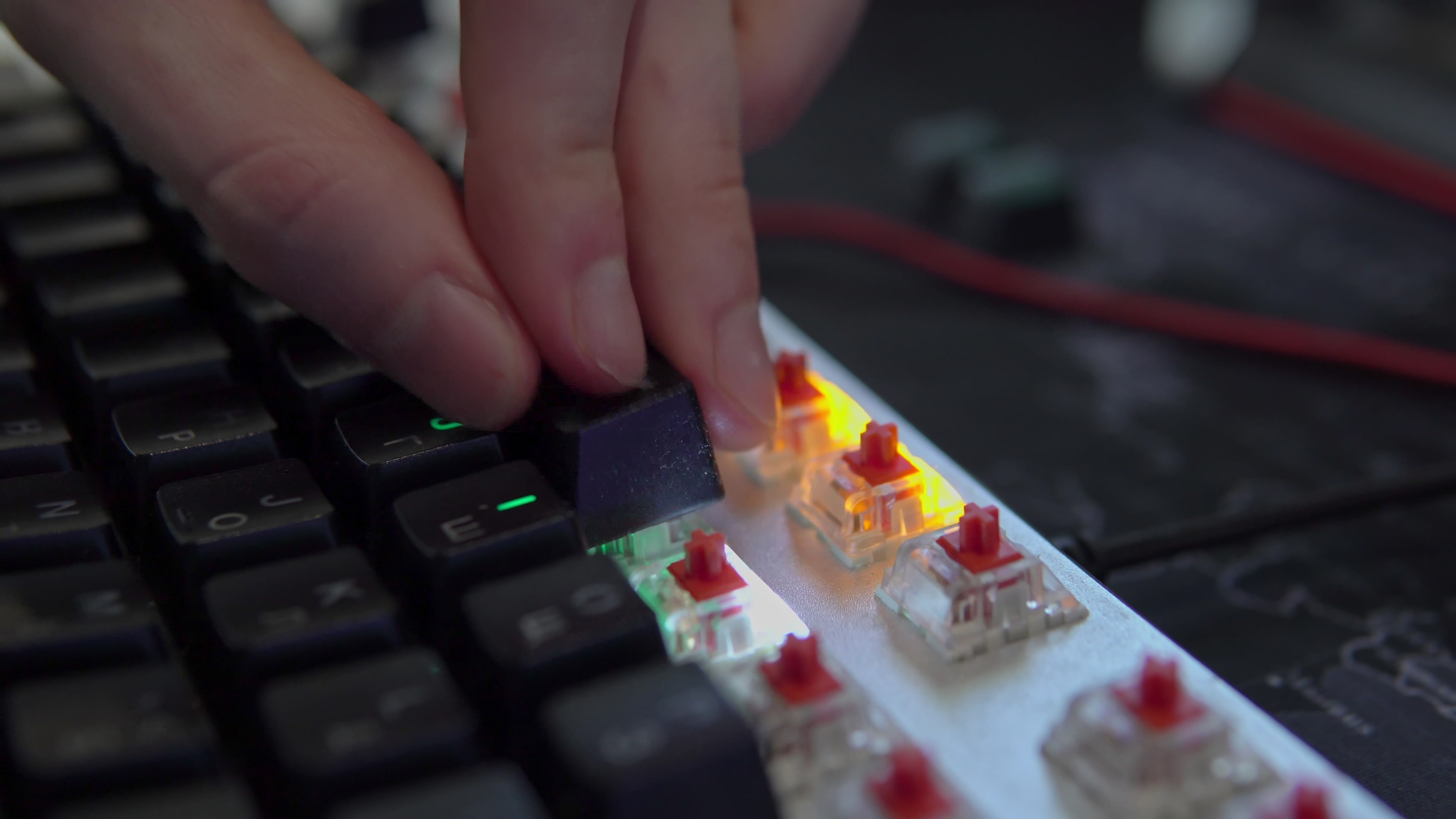 A human's hand assembles the keys of a mechanical keyboard with red switches, close-up shots and in motion 4k