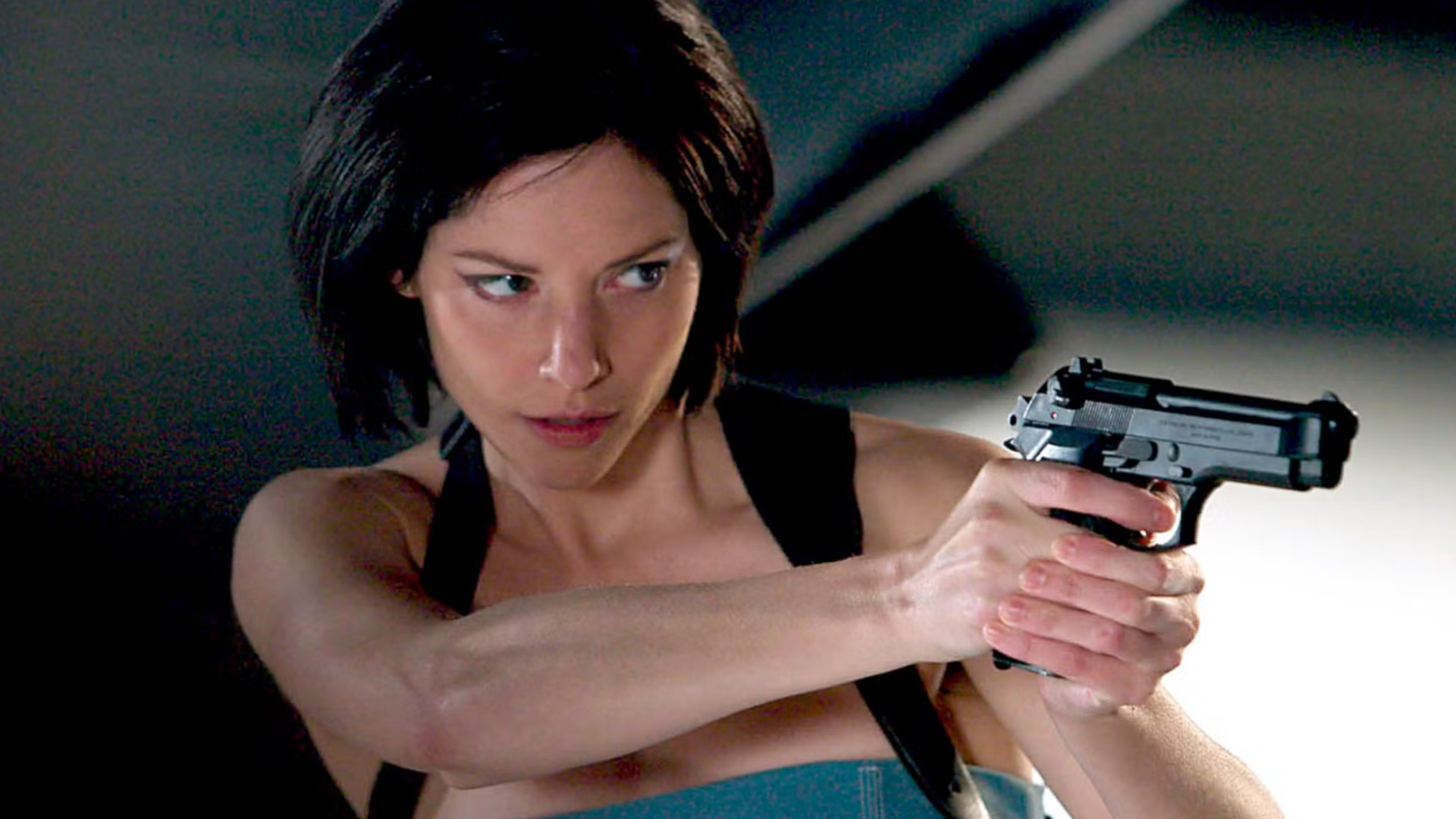 Sienna Guillory as Jill Valentine holding a gun during a scene in Resident Evil Apocalypse
