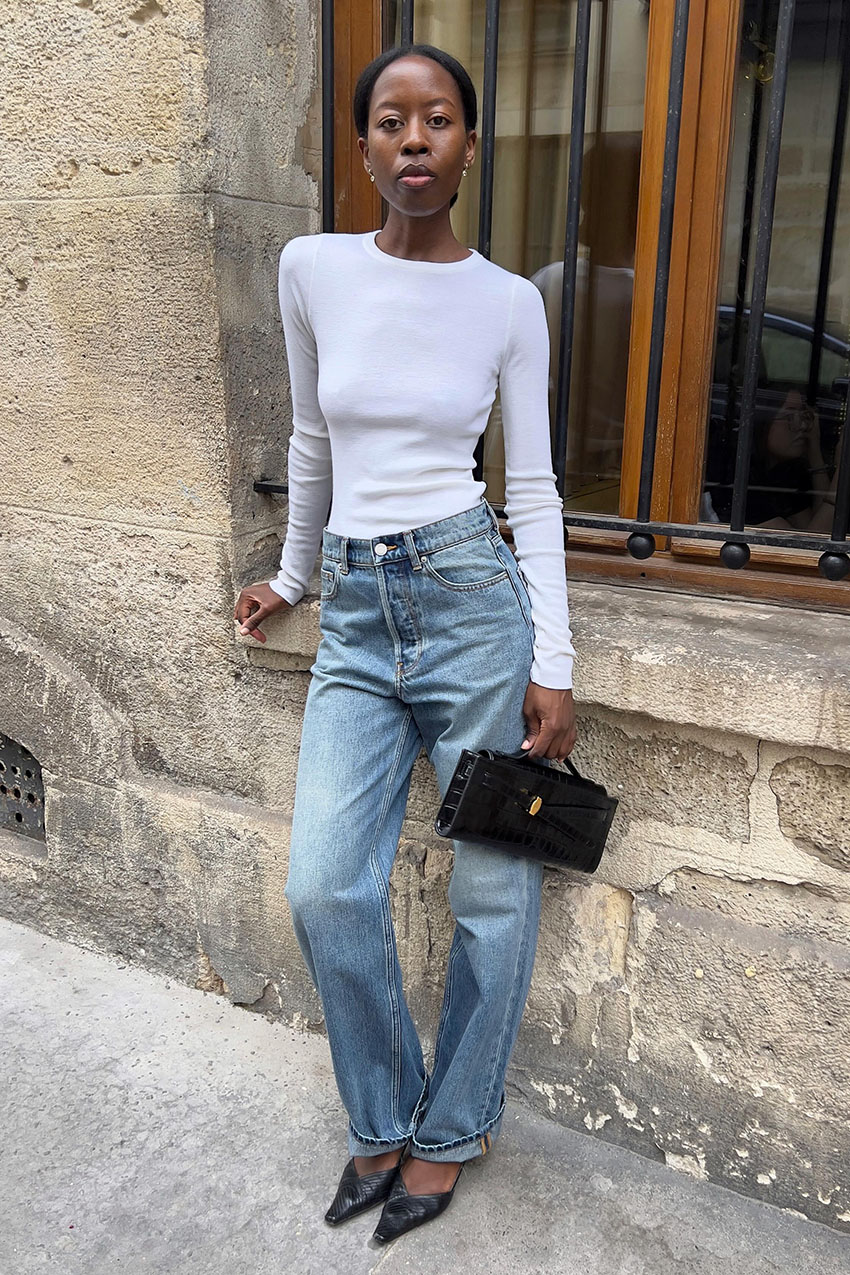 a woman wearing white long-sleeve top, jeans, and heels