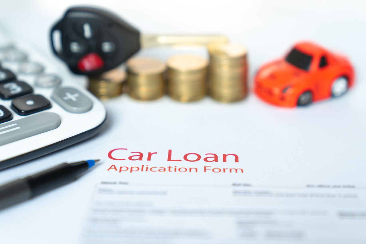 Car finance application form with some coins, a toy car, some keys and a calculator.