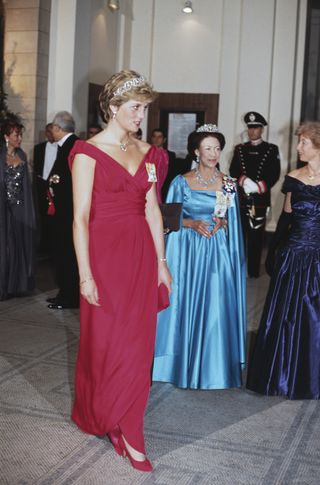 Princess Diana wears a red dress and Princess Margaret wears a teal blue dress