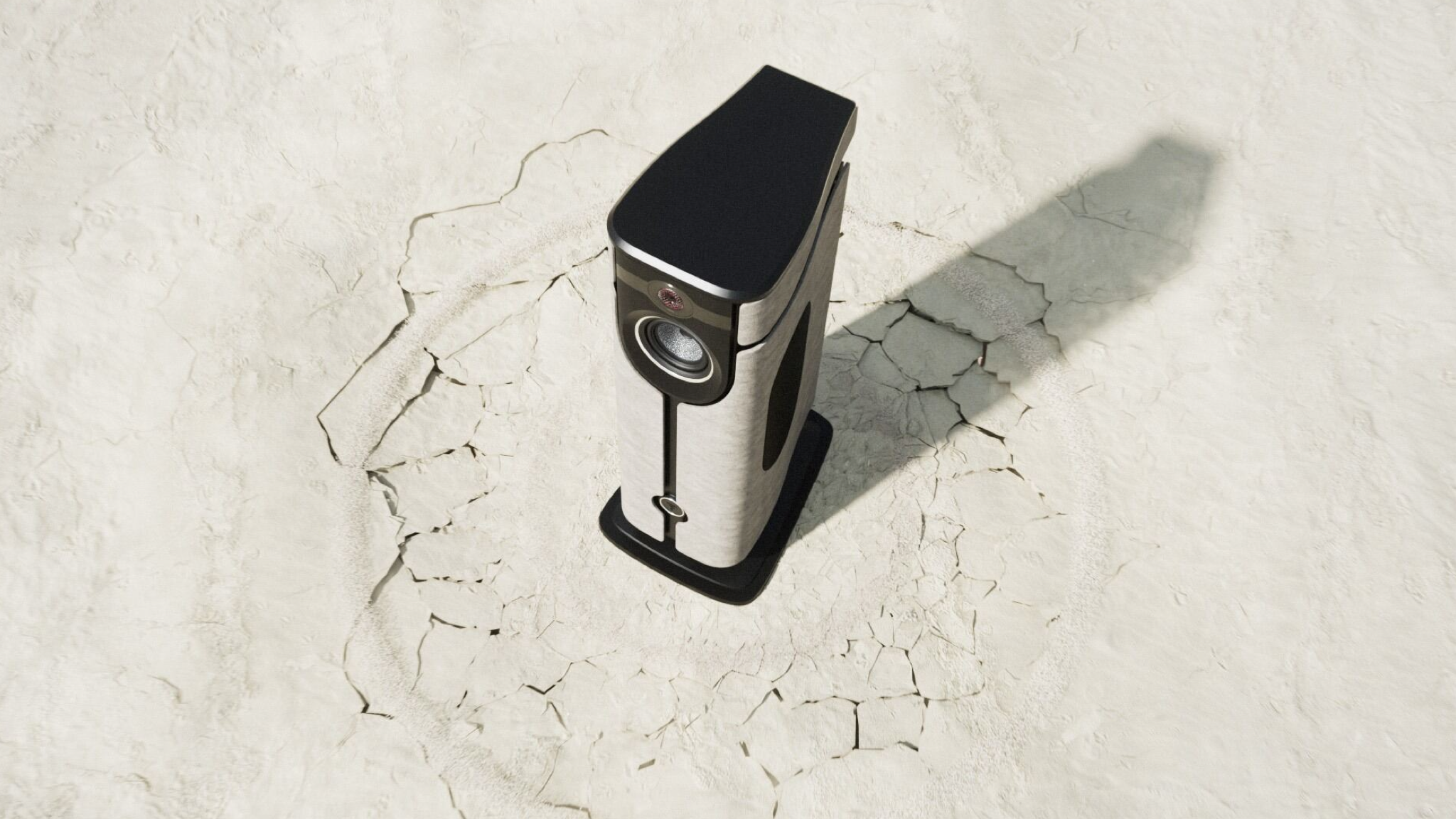 Lifestyle image of the Focal Diva Mezza Utopia on sandy/rocky ground. The ground is cracked to suggest that the speaker has arrived with a big impact