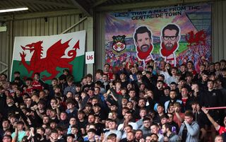 Wrexham supporters in front of a banner featuring Ryan Reynolds and Rob McElhenney
