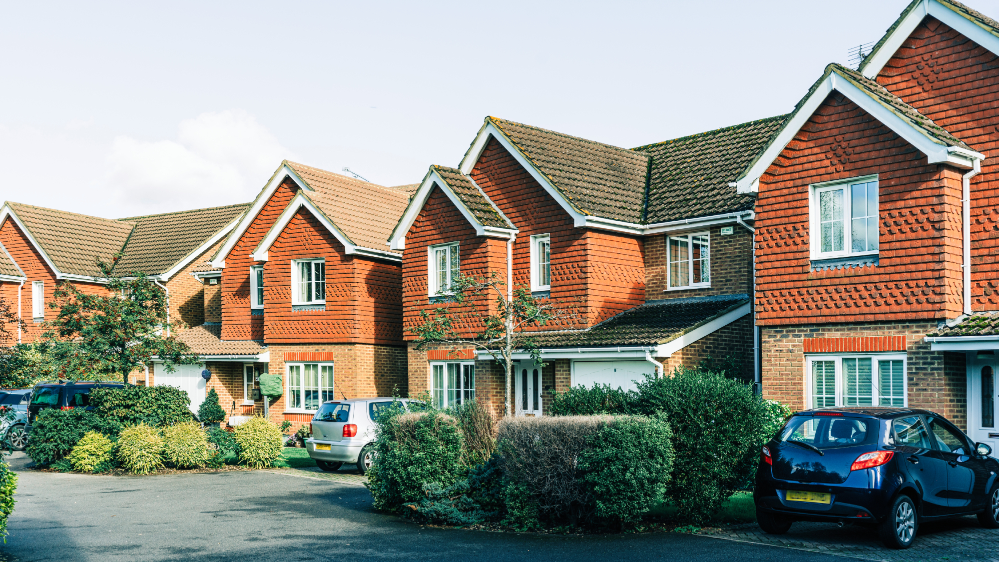 residential street with brick houses with small front gardens and driveways