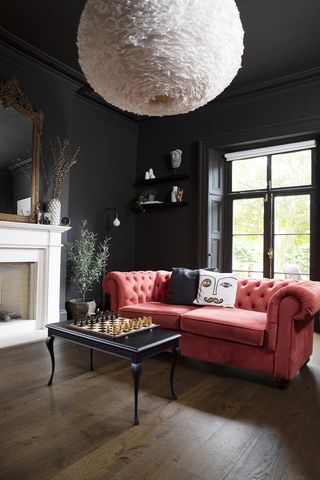 black living room with a pink sofa and a chessboard on the coffee table