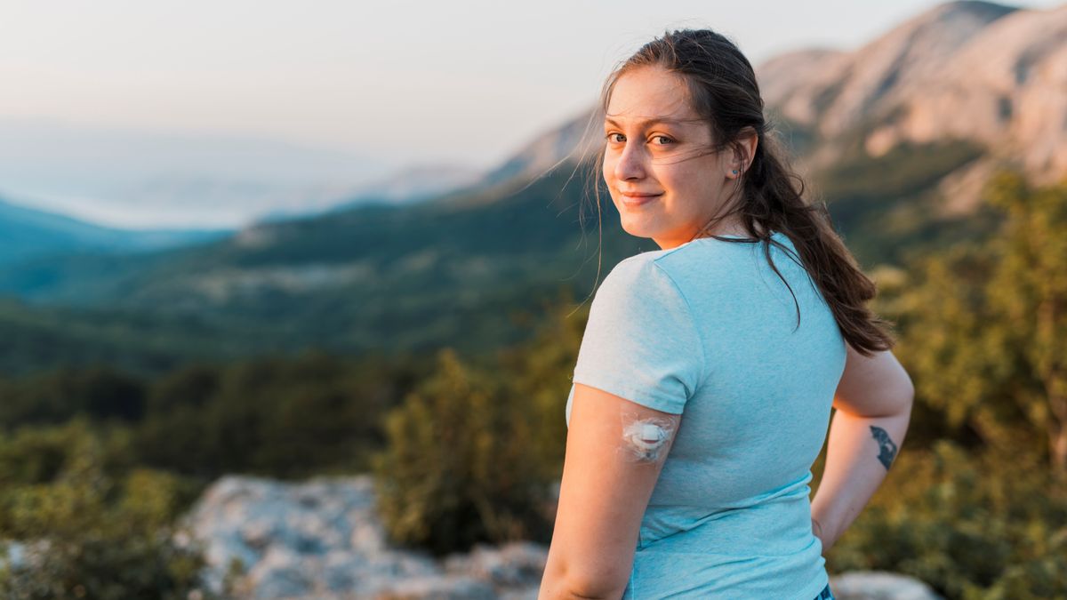 Woman with diabetes standing on top of the hill and looking at camera