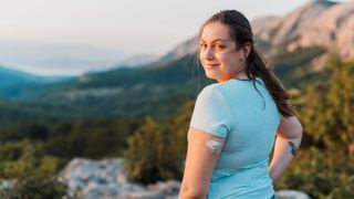 Woman with diabetes standing on top of the hill and looking at camera