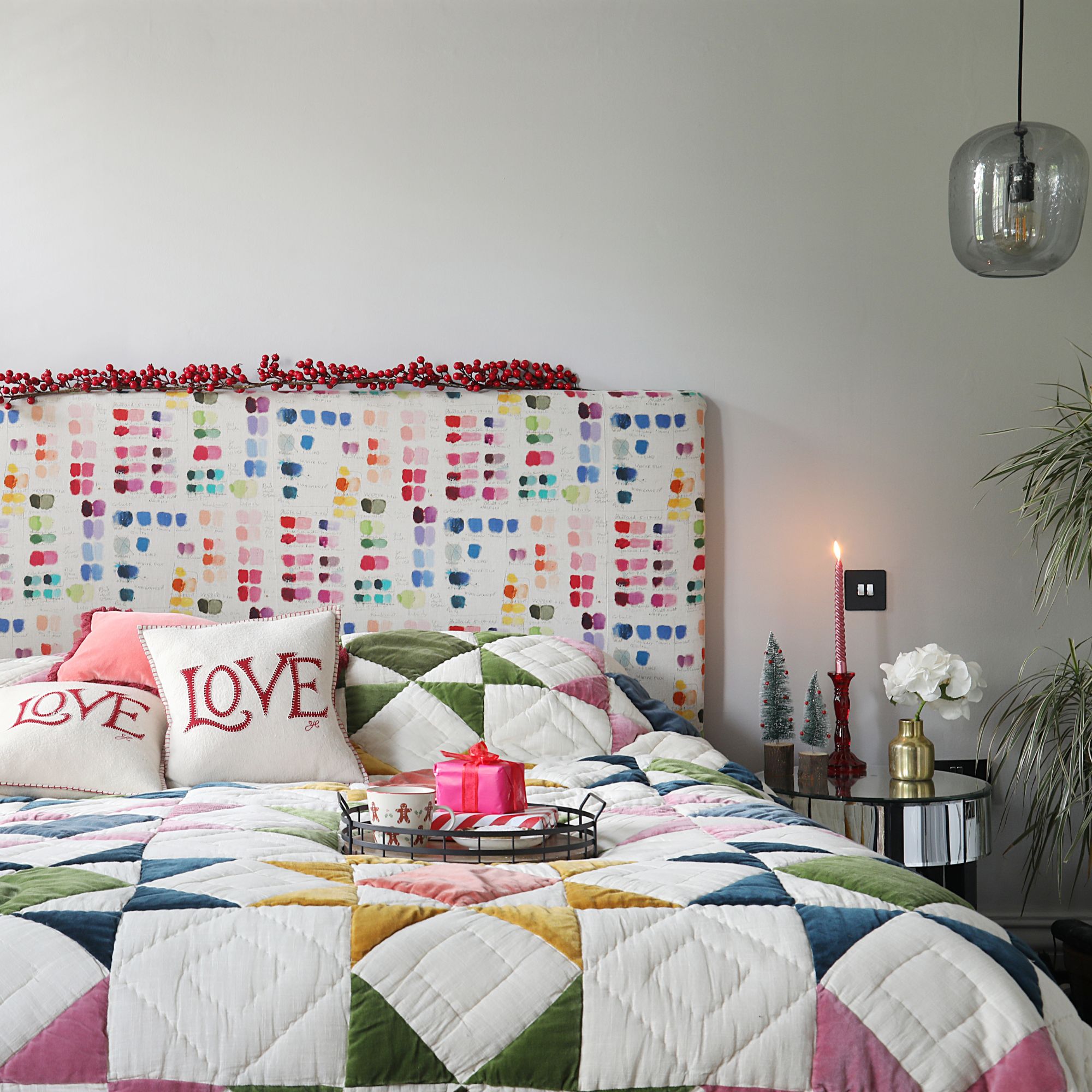 Colourful bedroom with patchwork quilt and a colourful headboard, with a tray and a present on top of it