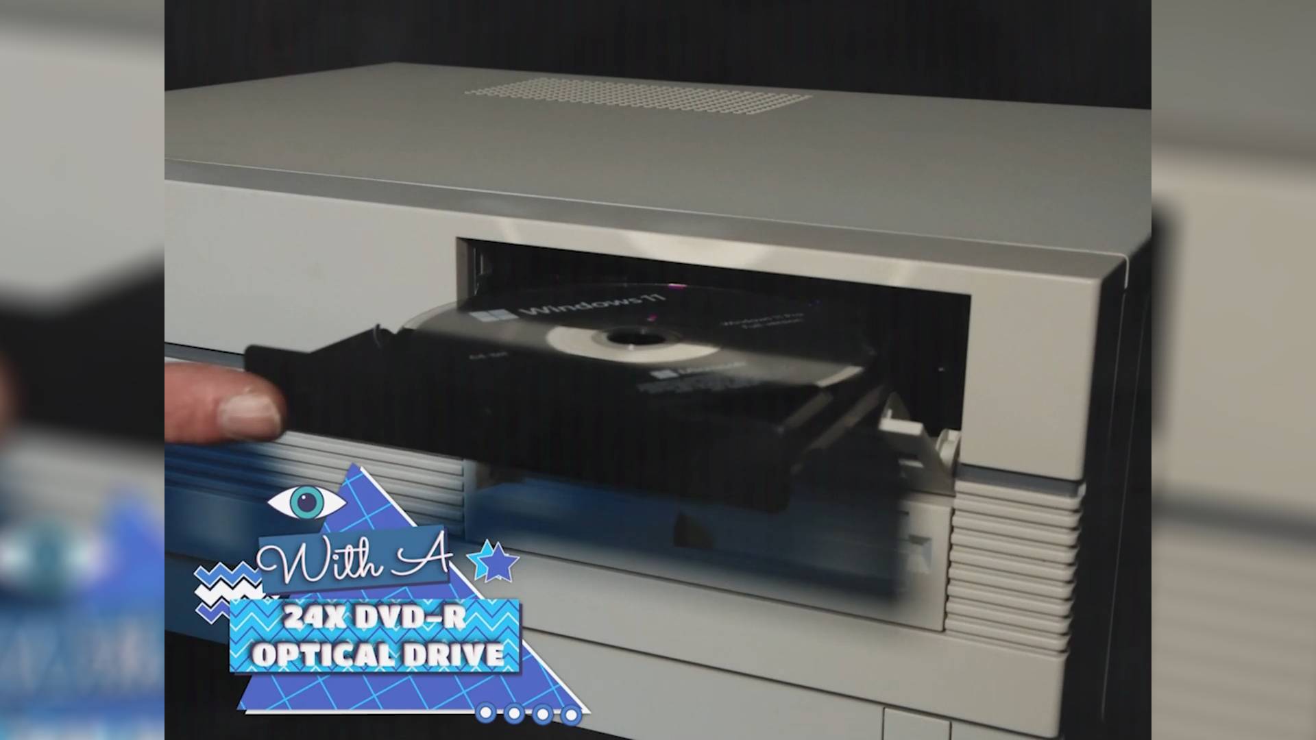 Finger pushing Maingear Retro95 PC DVD drive with disc in tray.