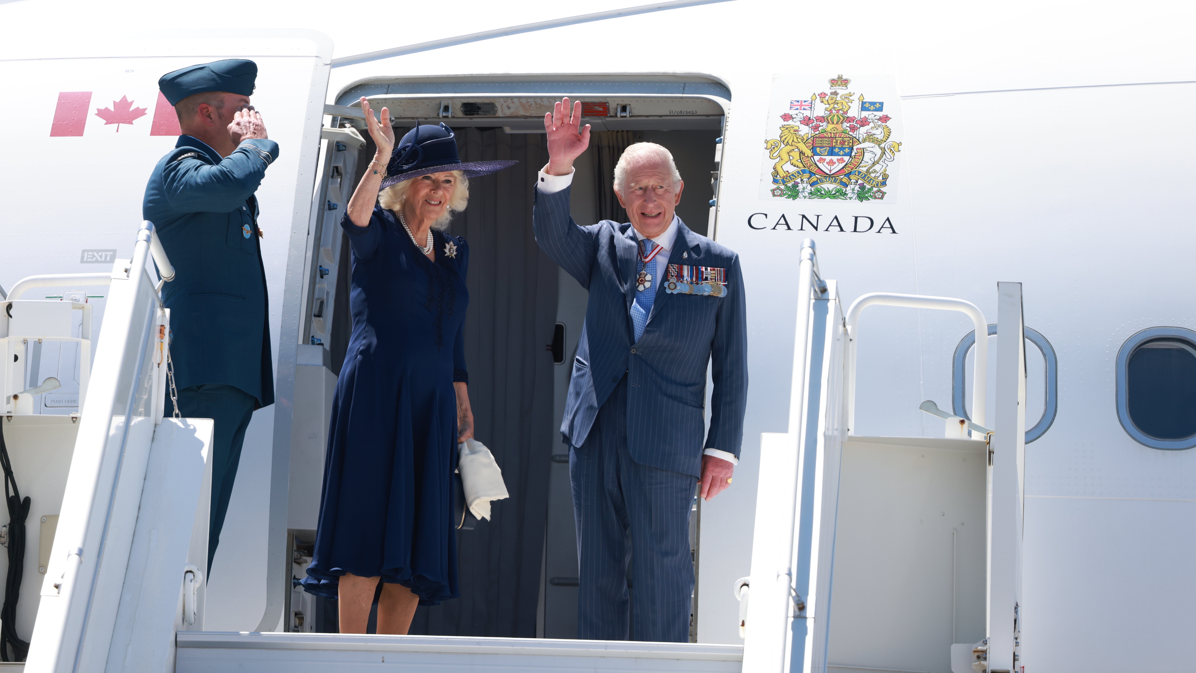 King Charles III and Queen Camilla wave goodbye as they enter the airplane at the end of an official visit to Canada on May 27, 2025