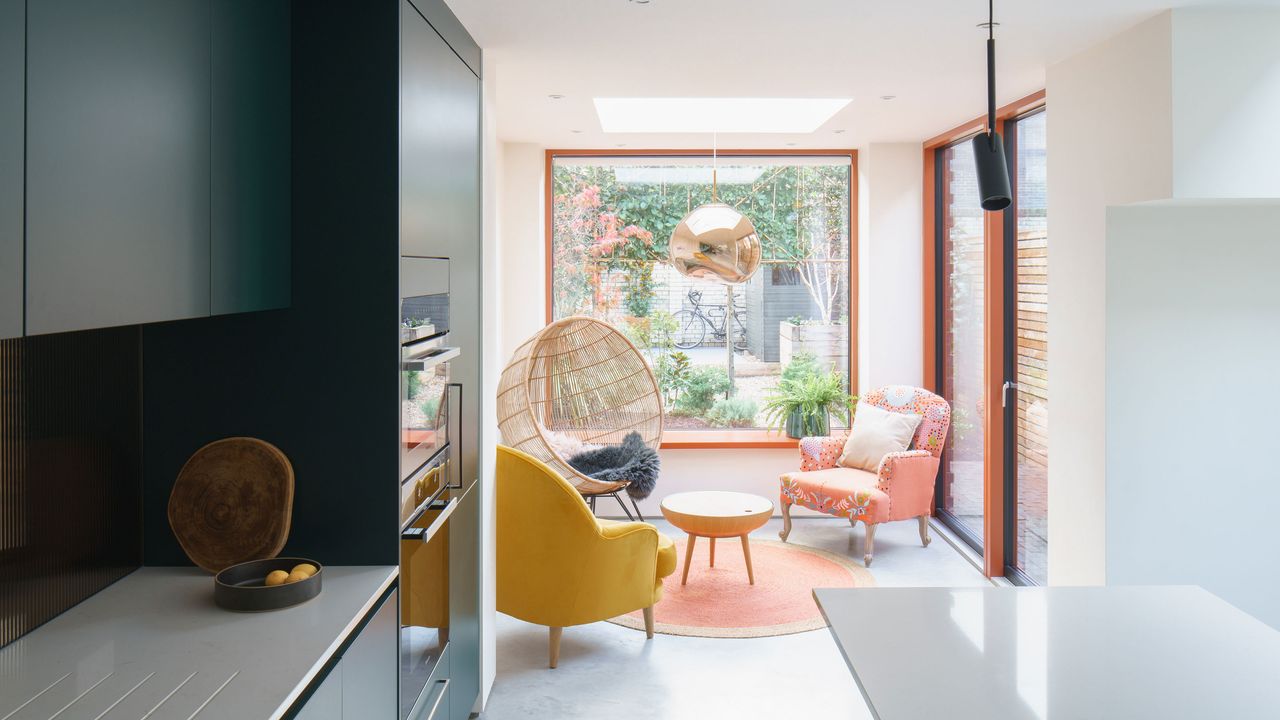 light and bright kitchen looking out into a seating area with armchairs and a large can chair