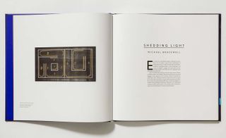 An open book with a black rectangular object with lines on it on the left page and text of the right page.