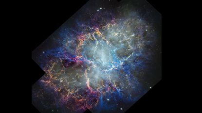 A glowing nebula of pink, blue and orange is seen in the darkness of space