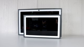 The original Echo Show 15 in front of the new Echo Show 21 with their screens turned off on a table