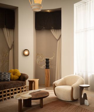 A living room with a brown couch, white armchair, and two interlocking coffee tables