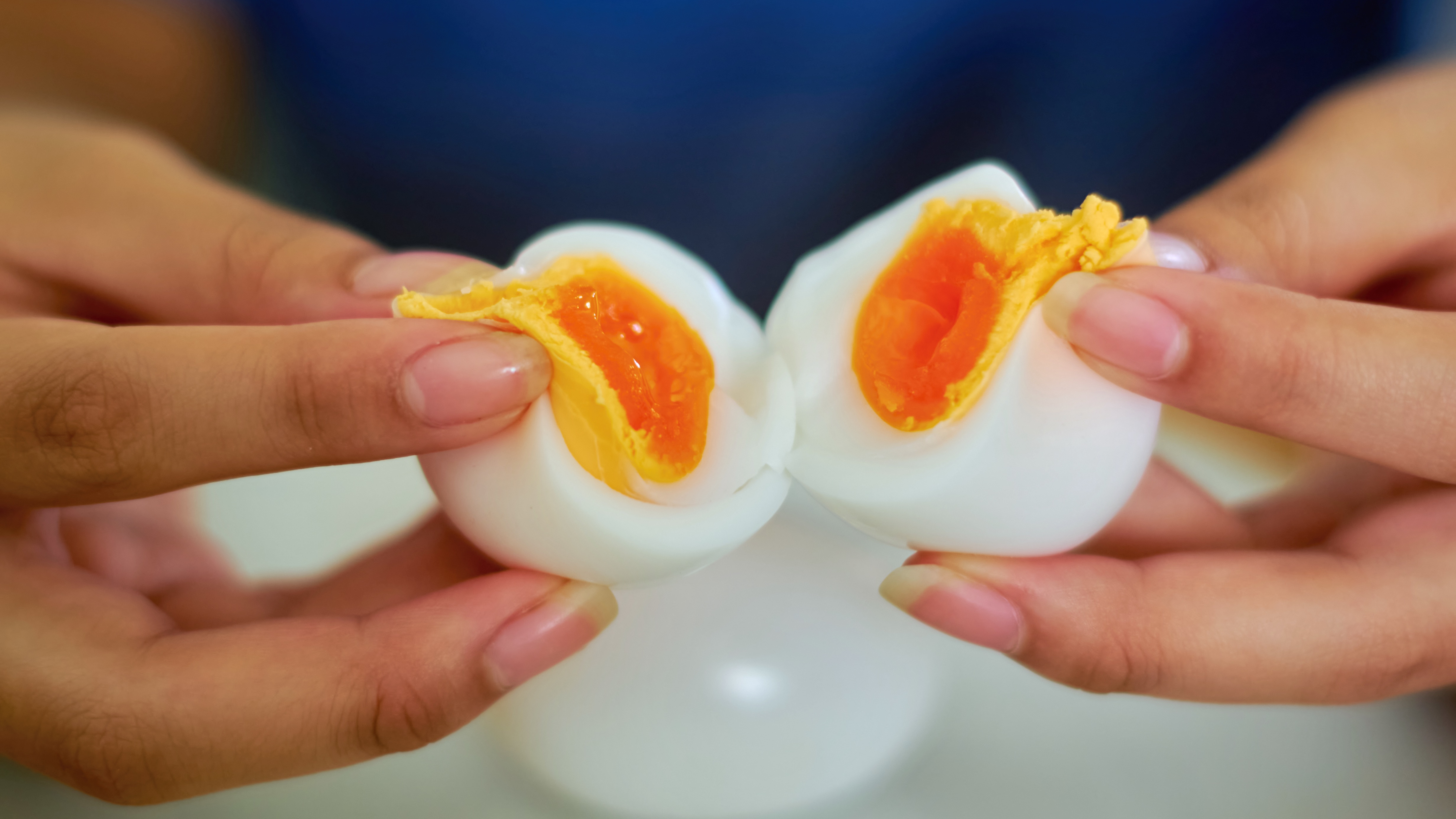 A woman splits a boiled egg in two.
