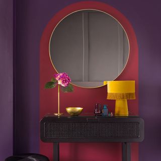 room with burgundy coloured wall and round mirror