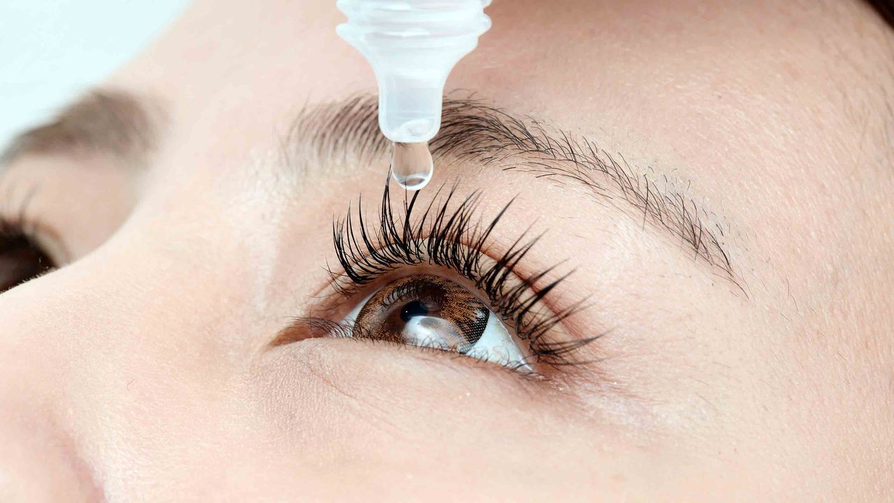 A woman puts Bausch + Lomb eyedrops into one eye