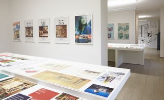 Archival material including adverts, sketches, photos and magazines are presented in glass vitrines