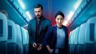 Dr Matthew Nolan (Richard Armitage), in handcuffs, stands behind DC Hana Li (Jing Luci) aboard an passenger plane in Red Eye