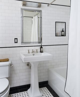 A bathroom with white tiled walls and black tiled accents