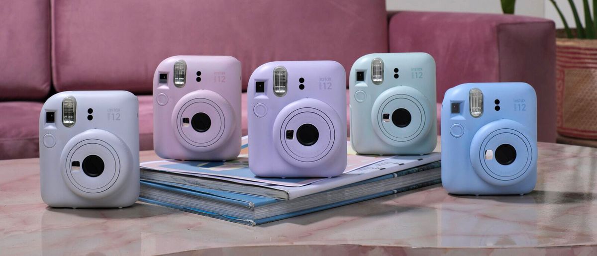 The Fujifilm Instax Mini 12 on a table with each of its five color choice