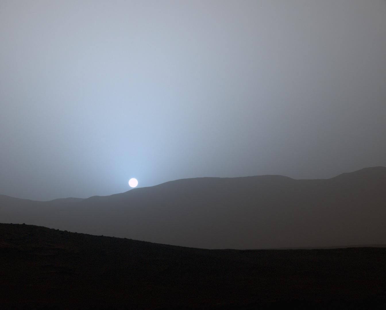 A sunset view with a silhouette of a mountain range in front.