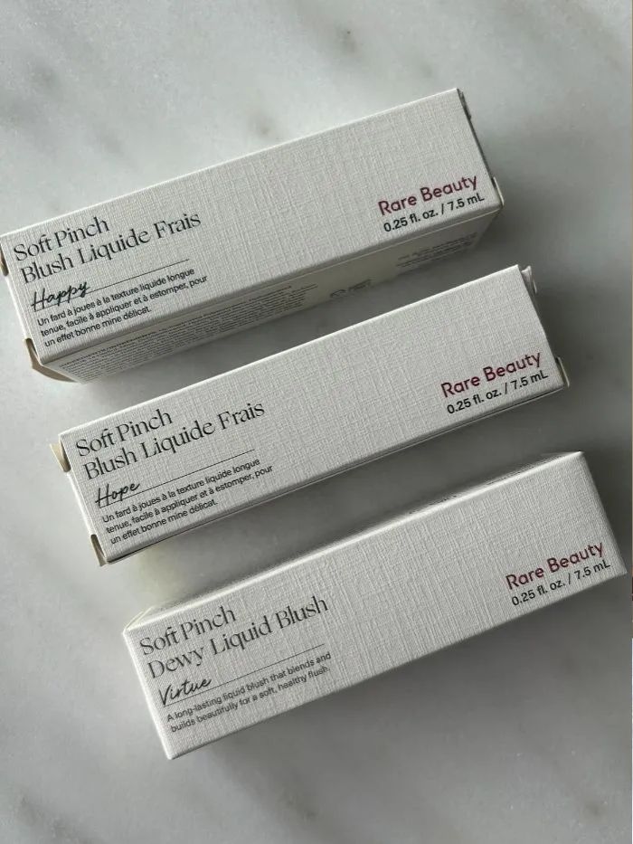Three of the Rare Beauty Soft Pinch Liquid Blushers on a marble background
